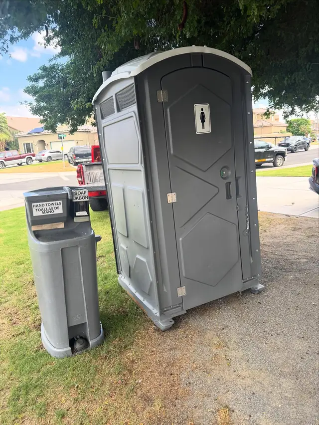 Gray porta potty with a hand-wash station