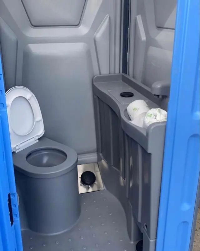 Gray toilet seat and shelf with toilet paper rolls inside a deluxe unit