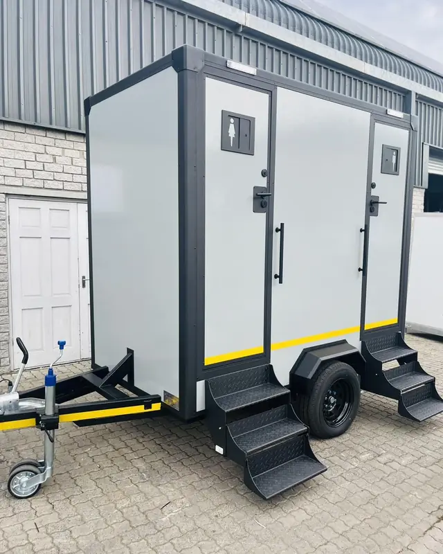 Exterior of a white two-stall restroom trailer with steps on each side